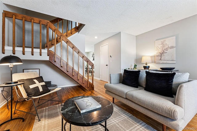 living area with stairs, a textured ceiling, wood finished floors, and baseboards