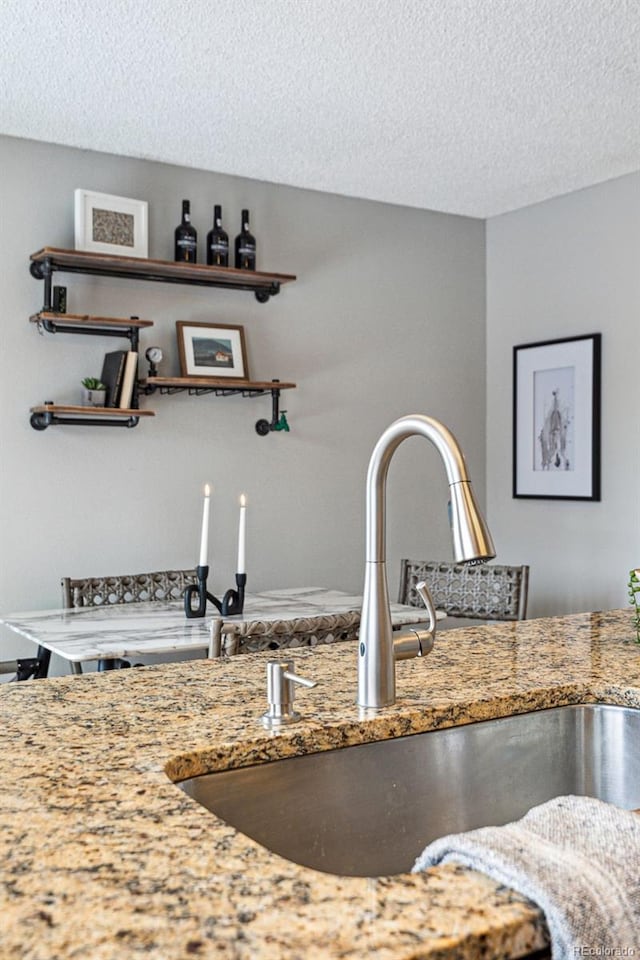 interior space featuring stone counters, a textured ceiling, open shelves, and a sink