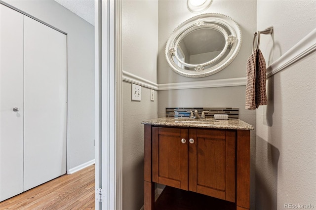 bathroom with a textured wall, wood finished floors, and vanity