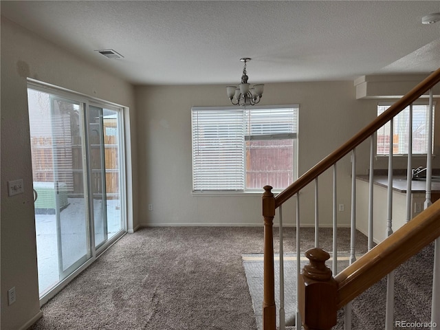 stairs with baseboards, visible vents, an inviting chandelier, a textured ceiling, and carpet floors