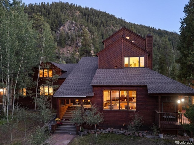82 Lenawee Ln, Dillon, CO 80435 - view of front of home featuring a forest view, a shingled roof, a chimney, stairs, and covered porch