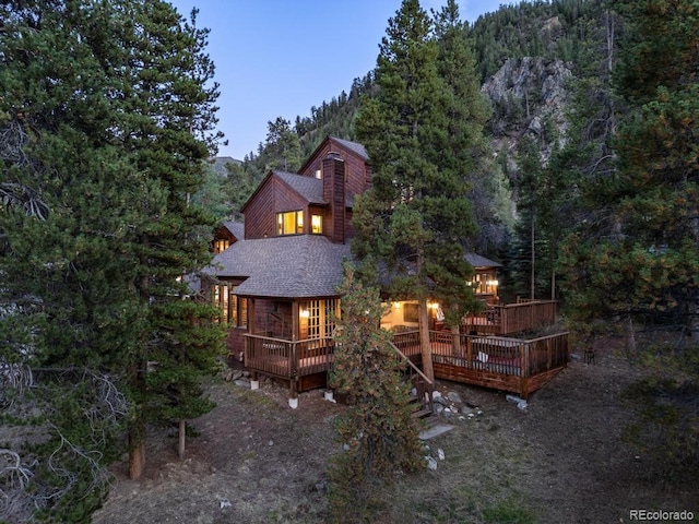 82 Lenawee Ln, Dillon, CO 80435 - back of property featuring a shingled roof, a deck, and a forest view