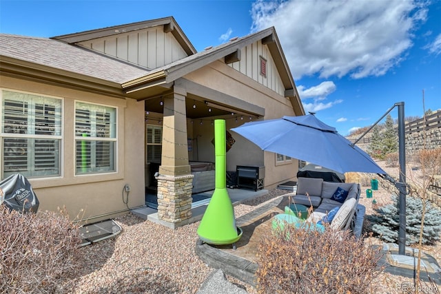 exterior space featuring stucco siding, a patio, board and batten siding, and a shingled roof