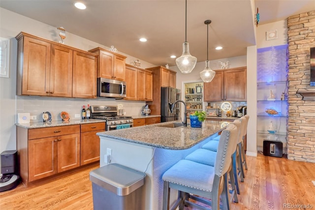 4544 Portillo Pl, Colorado Springs, CO 80924 - kitchen featuring a sink, light wood-style floors, stone counters, a kitchen bar, and appliances with stainless steel finishes