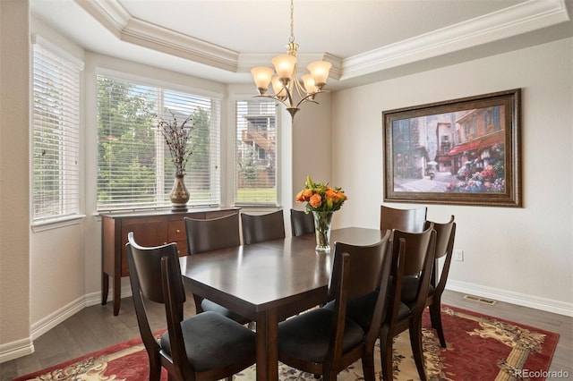 dining space with wood-type flooring, crown molding, a chandelier, and a tray ceiling