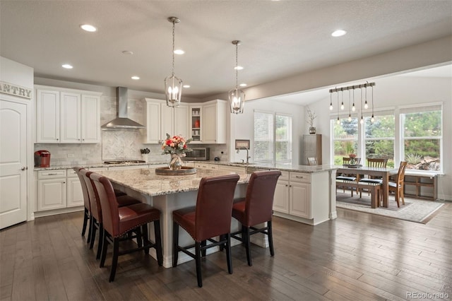 kitchen featuring white cabinetry, lofted ceiling, wall chimney range hood, dark hardwood / wood-style flooring, and appliances with stainless steel finishes