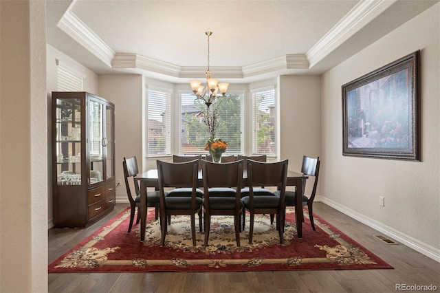 dining space featuring a chandelier, crown molding, a raised ceiling, and hardwood / wood-style floors