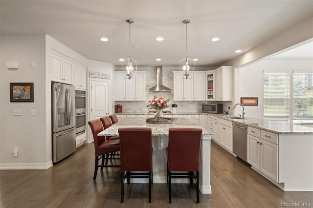 kitchen featuring tasteful backsplash, wall chimney range hood, dark hardwood / wood-style floors, a kitchen island, and appliances with stainless steel finishes