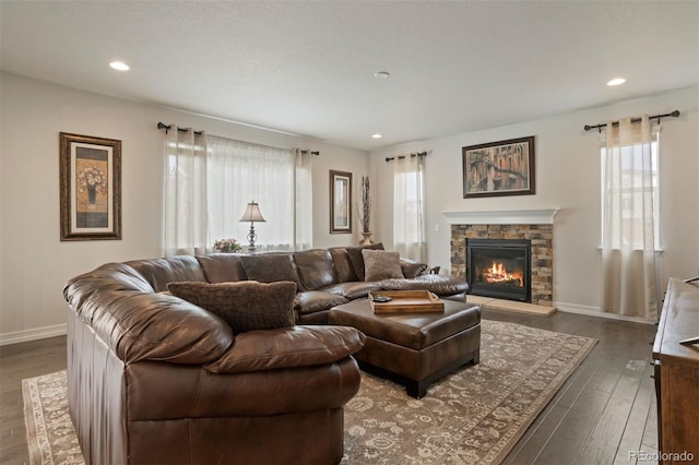 living room with a stone fireplace and dark hardwood / wood-style floors