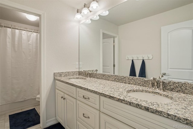 bathroom with dual vanity, toilet, and tile patterned floors