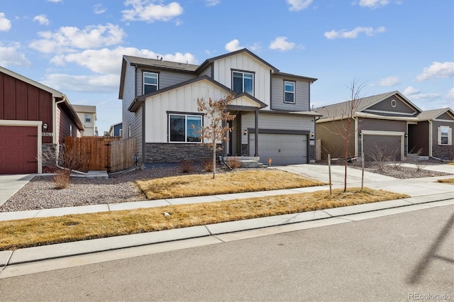 view of front of property featuring fence, concrete driveway, a garage, stone siding, and board and batten siding