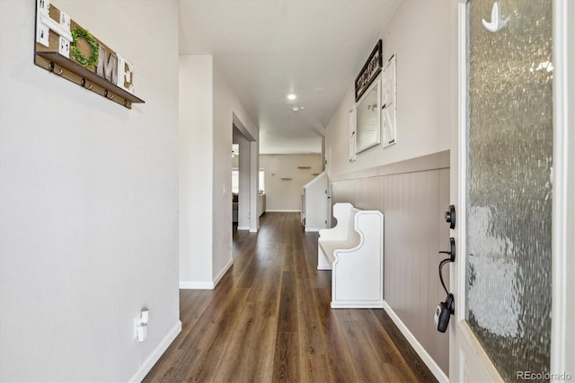 corridor featuring baseboards and dark wood finished floors