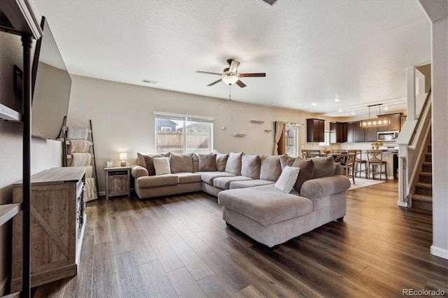 living room featuring dark wood-style floors, visible vents, ceiling fan, a textured ceiling, and stairs