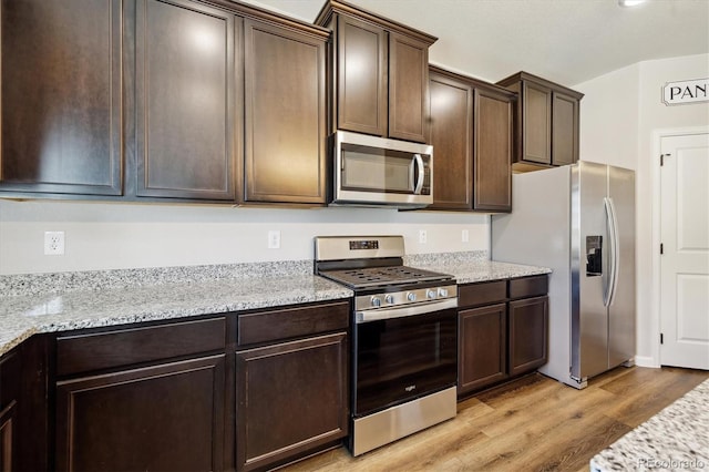 kitchen featuring stainless steel appliances, light wood-type flooring, dark brown cabinetry, and light stone countertops