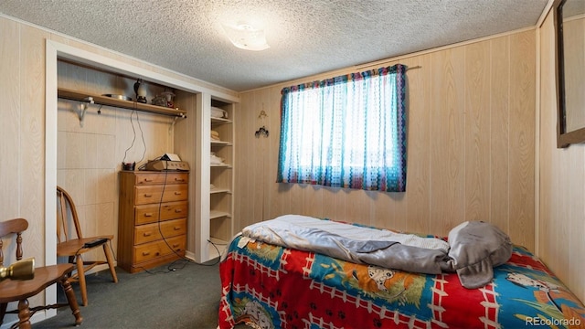 bedroom featuring dark carpet, a textured ceiling, and wooden walls