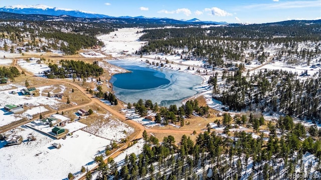 snowy aerial view with a water and mountain view