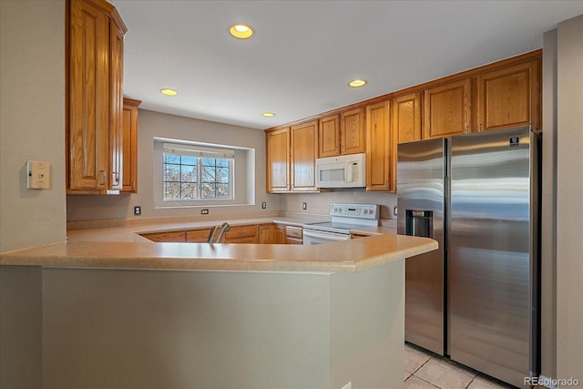 kitchen featuring sink, light tile patterned floors, white appliances, and kitchen peninsula