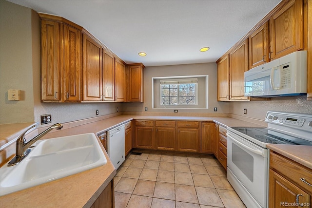 kitchen featuring sink, light tile patterned floors, and white appliances