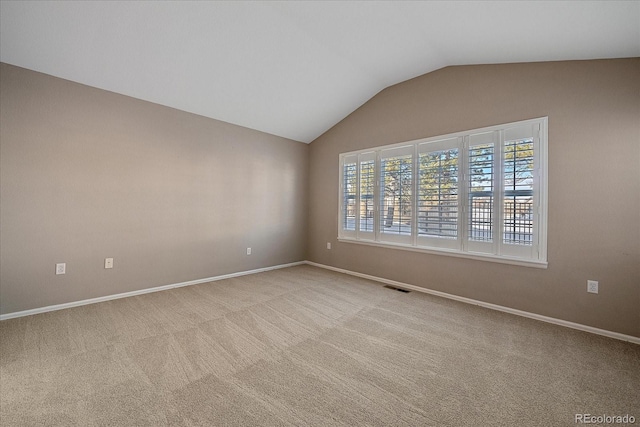 spare room featuring vaulted ceiling and light colored carpet