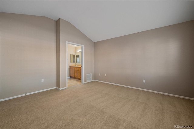 carpeted empty room featuring vaulted ceiling