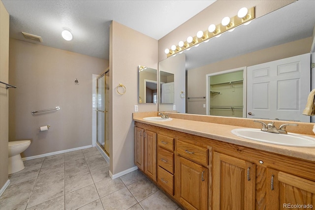 bathroom featuring vanity, toilet, tile patterned flooring, and a shower with door