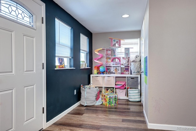 game room with a wealth of natural light and dark wood-type flooring