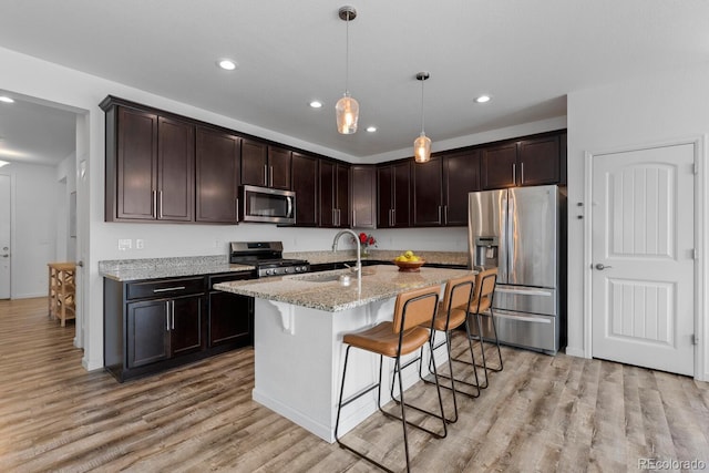 17960 Weymouth Ave, Parker, CO 80134 - kitchen with stainless steel appliances, light wood finished floors, dark brown cabinets, recessed lighting, and light stone counters