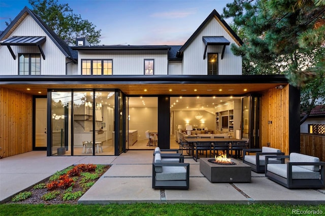 back house at dusk with a patio and an outdoor living space with a fire pit