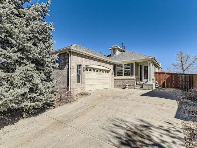 view of front of property with concrete driveway, an attached garage, fence, and roof with shingles