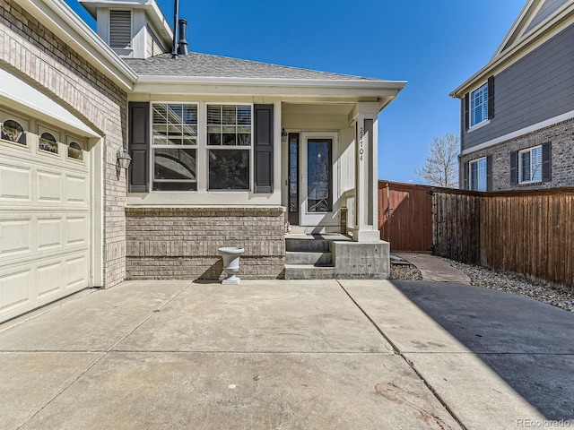 doorway to property with an attached garage, a shingled roof, and fence