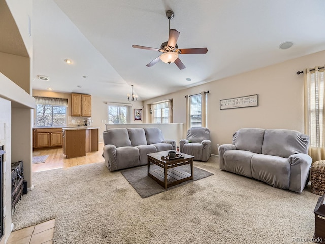 living room featuring light colored carpet, a tile fireplace, lofted ceiling, and a ceiling fan