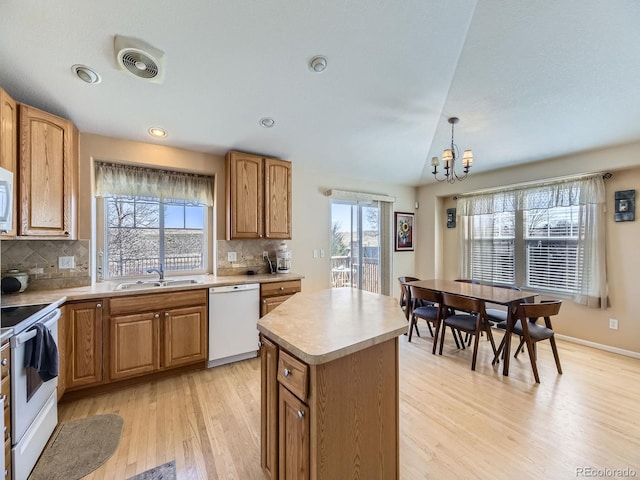 kitchen featuring visible vents, lofted ceiling, an inviting chandelier, white appliances, and a sink