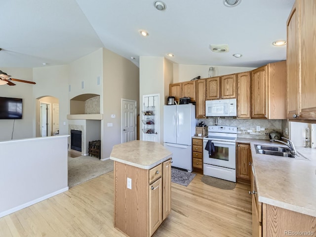 kitchen with white appliances, open floor plan, a kitchen island, and a sink