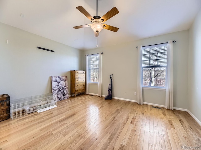 interior space with visible vents, a ceiling fan, light wood-type flooring, and baseboards