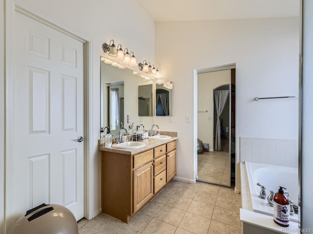 full bath with tile patterned flooring, double vanity, a garden tub, and a sink