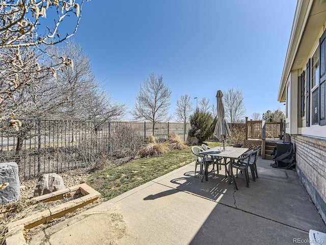 view of patio / terrace featuring outdoor dining area, a wooden deck, and a fenced backyard