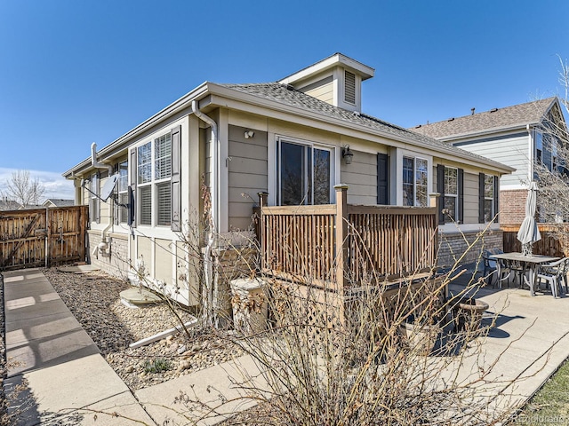 rear view of house featuring a shingled roof and a deck