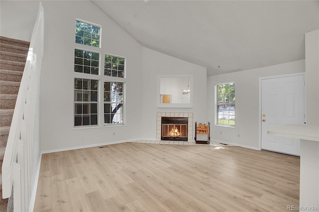 unfurnished living room with high vaulted ceiling, light hardwood / wood-style floors, and a tile fireplace