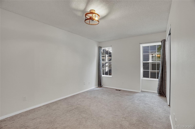 carpeted empty room featuring a textured ceiling