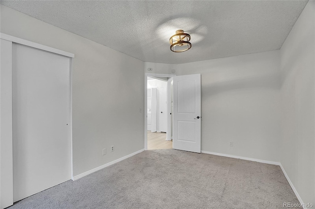 unfurnished bedroom with a closet, light colored carpet, and a textured ceiling