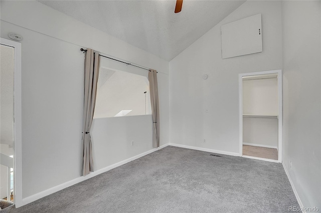 carpeted empty room with a textured ceiling, ceiling fan, and vaulted ceiling