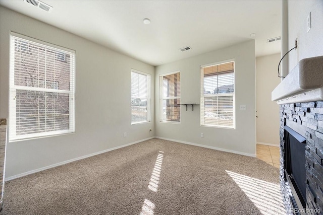 unfurnished living room featuring a stone fireplace and light carpet