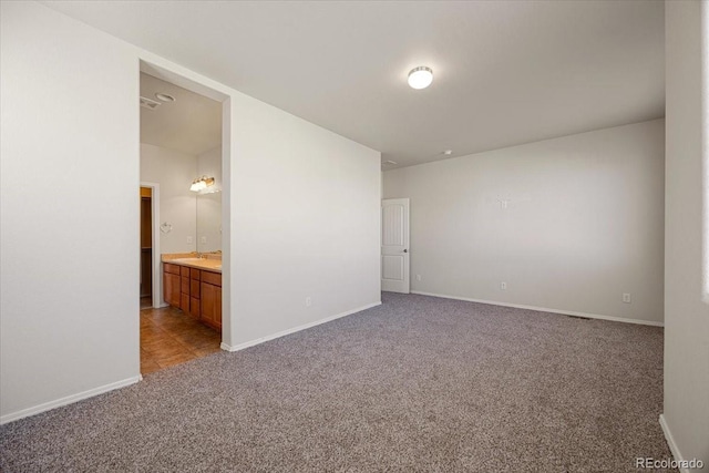 unfurnished bedroom with sink, carpet floors, and ensuite bathroom