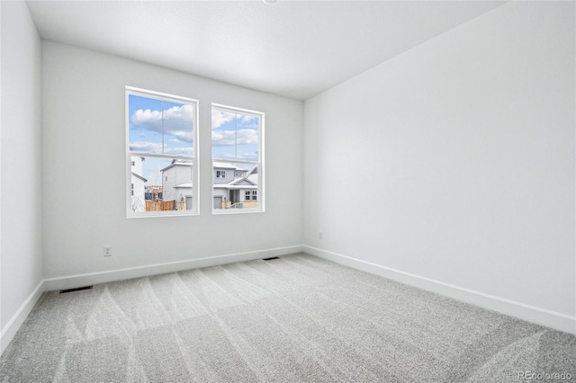 carpeted spare room featuring visible vents and baseboards