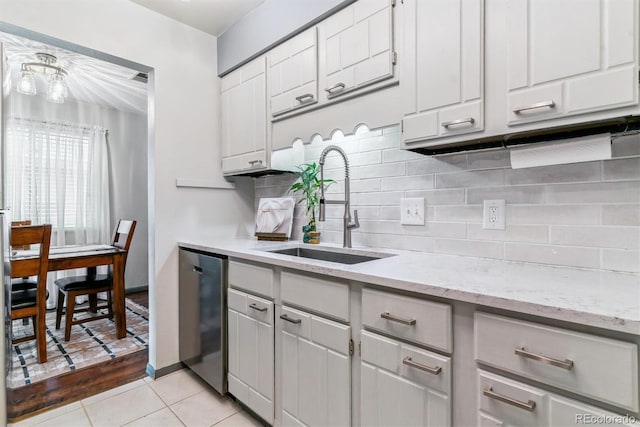 7995 E Mississippi Ave Unit C11, Denver, CO 80247 - kitchen with light stone counters, a sink, stainless steel dishwasher, light tile patterned floors, and decorative backsplash