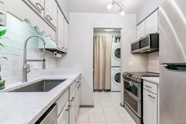 7995 E Mississippi Ave Unit C11, Denver, CO 80247 - kitchen featuring stacked washer and clothes dryer, light tile patterned floors, stainless steel appliances, a sink, and white cabinets