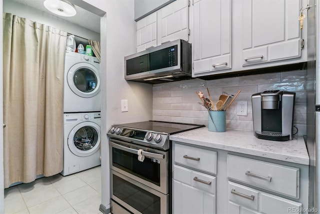 7995 E Mississippi Ave Unit C11, Denver, CO 80247 - kitchen with light tile patterned flooring, stacked washer and clothes dryer, stainless steel appliances, white cabinets, and decorative backsplash