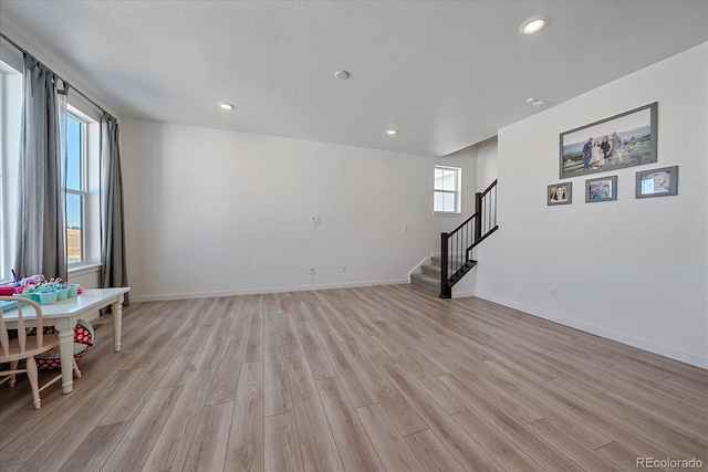 unfurnished room with a textured ceiling and light wood-type flooring