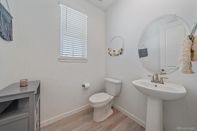 bathroom featuring toilet, wood-type flooring, and sink