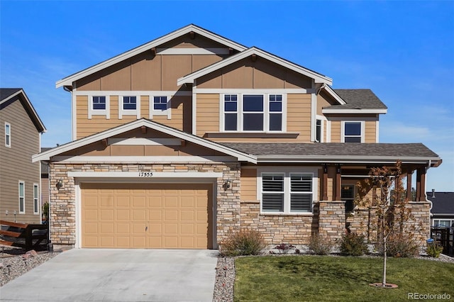 craftsman-style house featuring a shingled roof, a garage, stone siding, driveway, and a front lawn